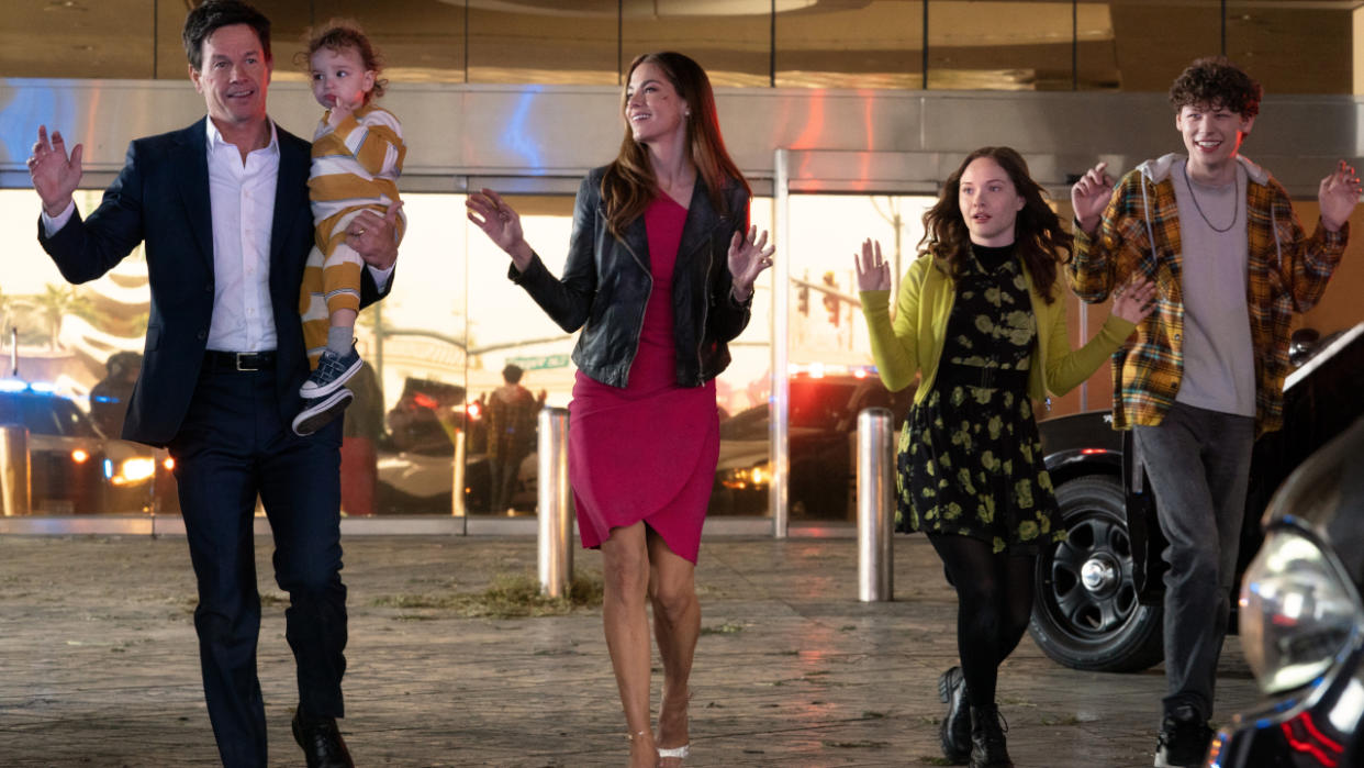  The Morgan family walks forward, with their hands in the air, in a deserted casino in The Family Plan. 