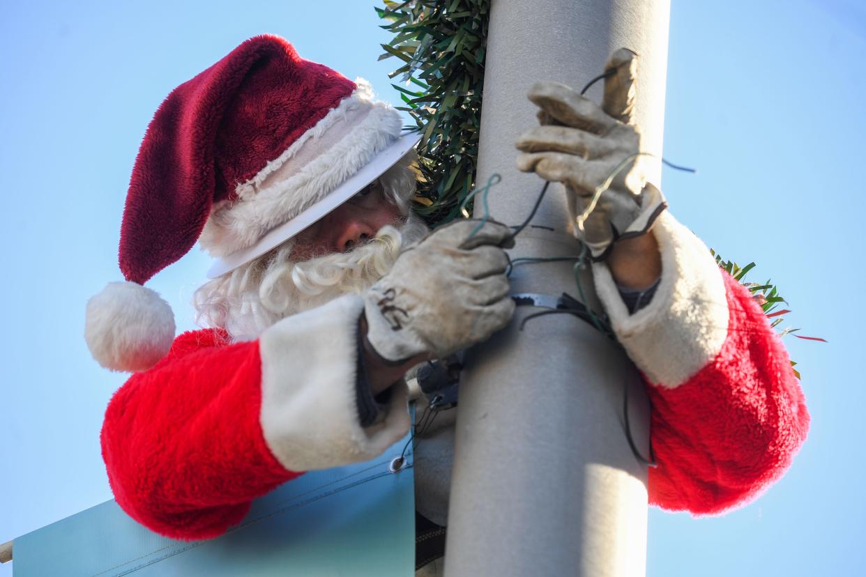 Sioux Falls City Light and Power worker Andy Gerovac dressed up as Santa to help decorate downtown with garland and wreaths while Ryan Faber drove him around on Friday, Nov. 17, 2023 in Sioux Falls.