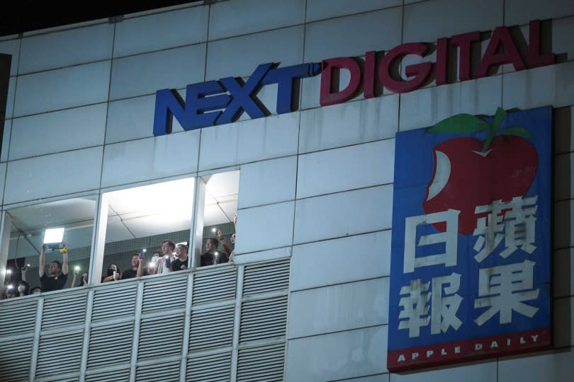 在蘋果日報總部及其出版商Next Digital宣布將印刷最後一版後，工作人員點亮手機手電筒，並向大樓外的支持者揮手致意。（圖／達志／路透社）