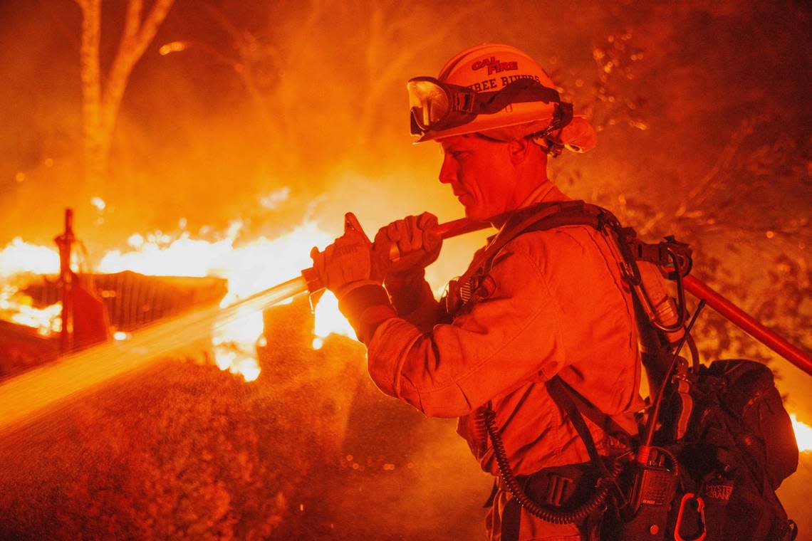 Firefighter Justin Montgomery defends a home on Triangle Road as the Oak Fire burns in unincorporated Mariposa County, Calif., on Friday, July 22, 2022.