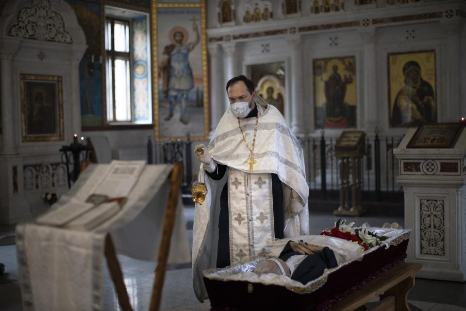 In this photo taken on Tuesday, June 2, 2020, Father Vasily Gelevan conducts a funeral service for a person who died of apoplexy at the Church of the Annunciation of the Holy Virgin in Sokolniki in Moscow, Russia. Russian Orthodox Churches in Moscow have been closed for parishioners since April 13 due to the coronavirus pandemic. (AP Photo/Alexander Zemlianichenko)