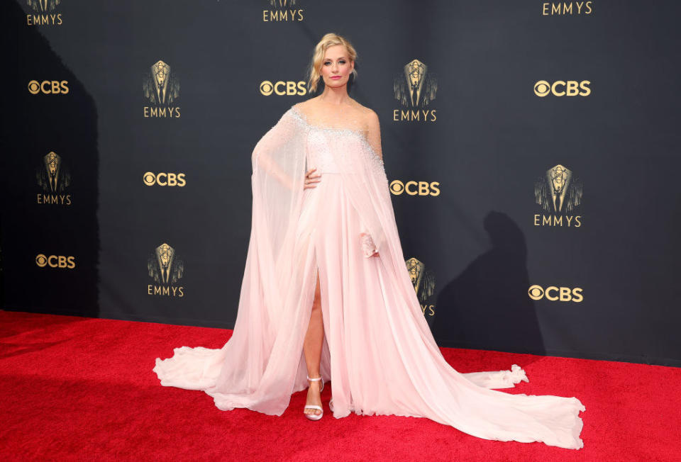Beth Behrs on the red carpet in a flowing pink gown with a high slit