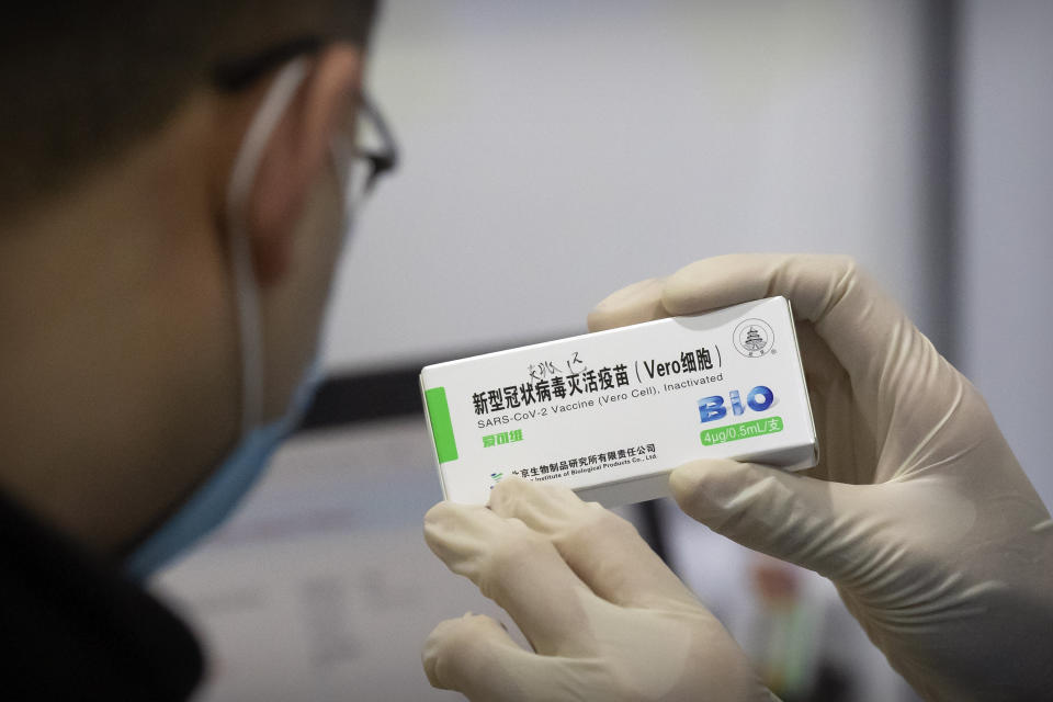 A medical worker shows the box for a coronavirus vaccine to a patient at a vaccination facility in Beijing, Friday, Jan. 15, 2021. A city in northern China is building a 3,000-unit quarantine facility to deal with an anticipated overflow of patients as COVID-19 cases rise ahead of the Lunar New Year travel rush. (AP Photo/Mark Schiefelbein)