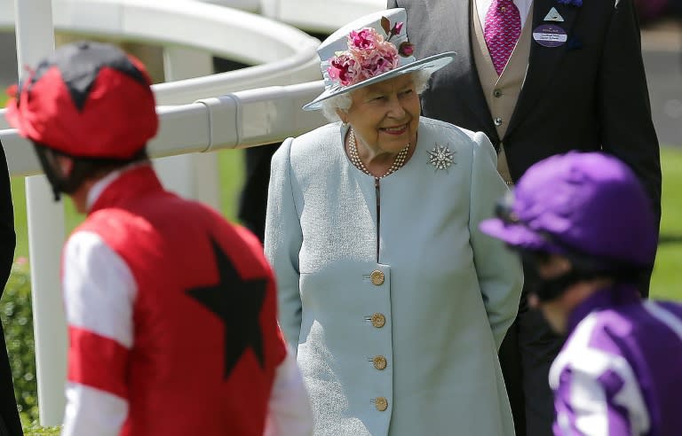 Britain's Queen Elizabeth II (C) reacts as jockeys and horses parade in the ring on the second day of the Royal Ascot horse racing meet, in Ascot, west of London, on June 20, 2018. The five-day meeting is one of the highlights of the horse racing calendar. Horse racing has been held at the famous Berkshire course since 1711 and tradition is a hallmark of the meeting. Top hats and tails remain compulsory in parts of the course while a daily procession of horse-drawn carriages brings the Queen to the course
