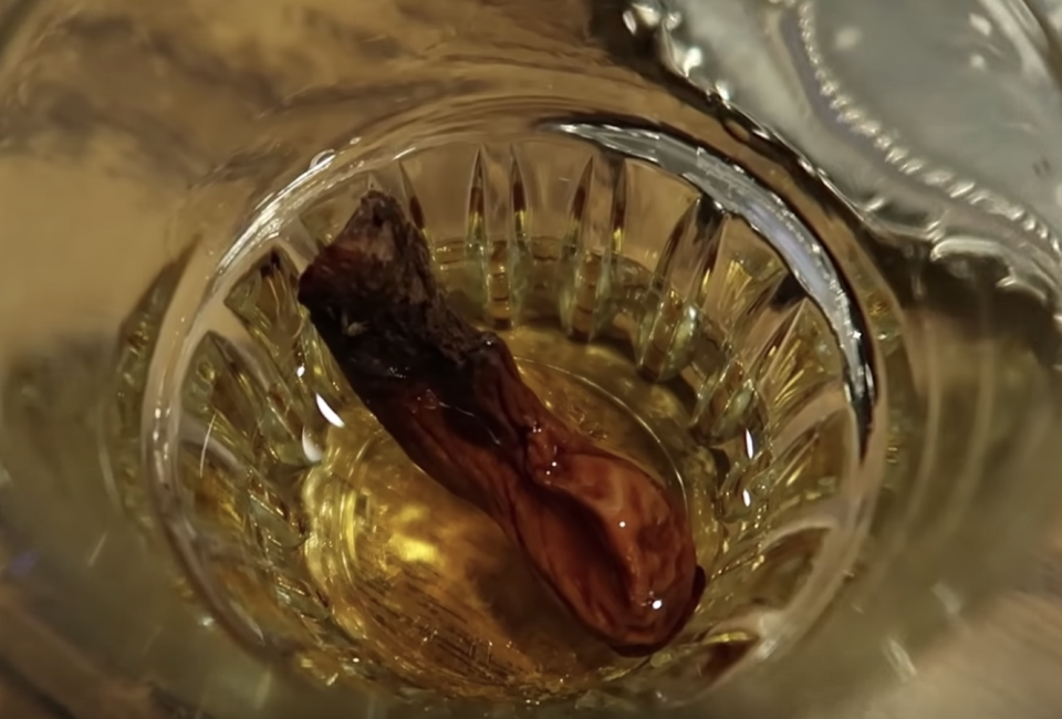 A mummified amputated toe bobs in a shot of whisky: Youtube: GRRRLTRAVELER | Christine Kaaloa