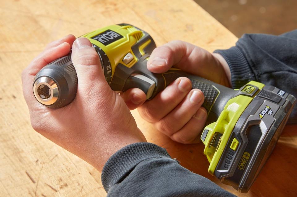 Handyperson squeezes the trigger on a cordless drill. 