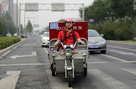 Richard Liu, CEO and founder of China's e-commerce company JD.com, rides an electric tricycle as he delivers goods for customers to celebrate the anniversary of the founding of the company, in Beijing, June 16, 2014. REUTERS/Jason Lee