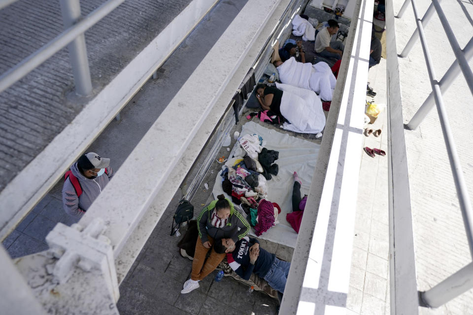 FILE - In this Thursday, March 18, 2021, file photo migrants who were caught trying to sneak into the United States and deported rest under a ramp that leads to the McAllen-Hidalgo International Bridge point of entry into the U.S. in Reynosa, Mexico. A surge of migrants on the Southwest border has the Biden administration on the defensive. The head of Homeland Security acknowledged the severity of the problem Tuesday but insisted it's under control and said he won't revive a Trump-era practice of immediately expelling teens and children. (AP Photo/Julio Cortez)