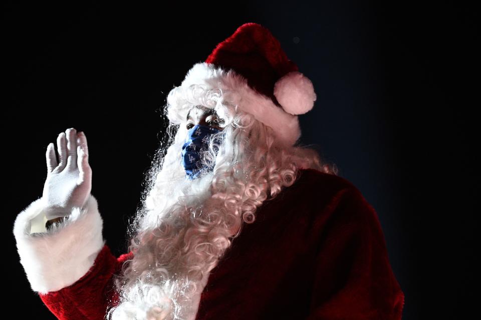 Santa Claus gestures to visitors in their cars as they attend the Dodgers Holiday Festival, a drive-thru light and performance experience honoring the Dodgers' baseball World Championship and celebrating the holiday season in a safe way amidst the coronavirus pandemic, December 2, 2020 at Dodgers Stadium in Los Angeles, California. (Photo by Robyn Beck / AFP) (Photo by ROBYN BECK/AFP via Getty Images)