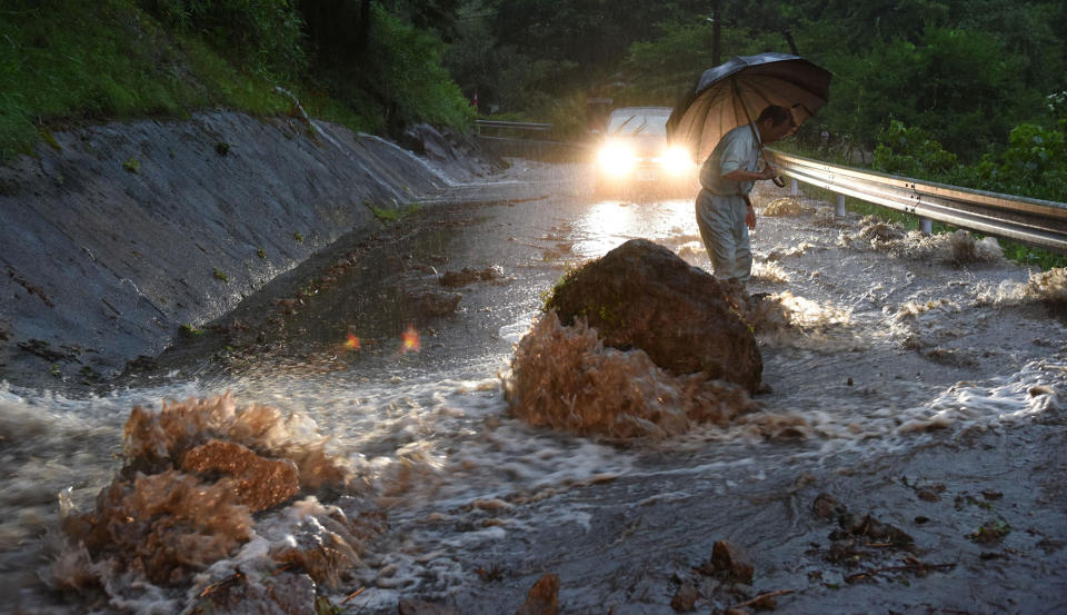 A man walks on a flooded road