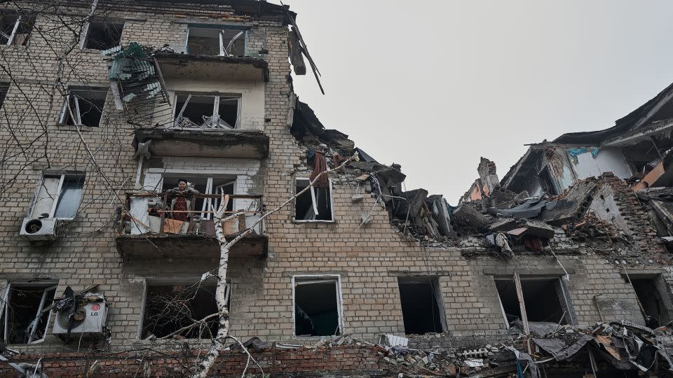 An elderly civilian woman stands with a cat on the balcony of her destroyed house in the Ukrainian city of Avdiivka on Thursday. She used to be a Ukrainian language teacher before the full scale invasion. - Vlada Liberova/Libkos/Getty Images