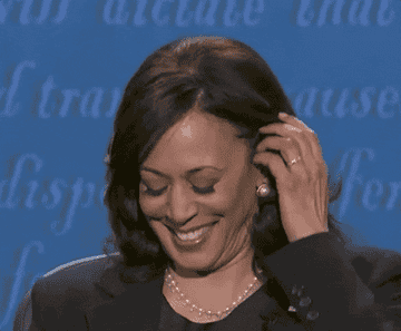 Vice President Kamala Harris tucking her hair behind her ears and putting her chin on her hands in an "I'm listening" way