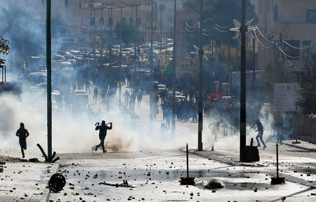 Palestinian protesters run for cover from tear gas fired by Israeli troops during clashes at a protest against U.S. President Donald Trump's decision to recognize Jerusalem as the capital of Israel, in the West Bank city of Bethlehem December 7, 2017. REUTERS/Mussa Qawasma