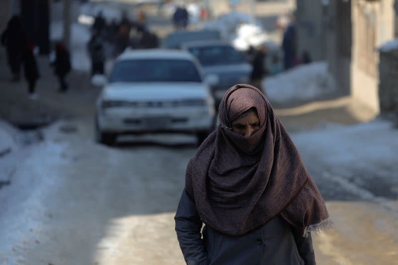 An Afghan woman walks on a snow-covered street on the TV mountain in Kabul