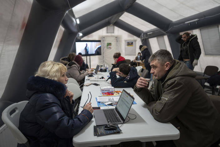A woman speaks to his colleague at the heating tent "Point of Invincibly" in Bucha, Ukraine, Monday, Nov. 28, 2022. (AP Photo/Evgeniy Maloletka)