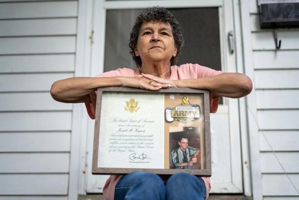 Theresa Kuznetz, of Wyandotte, sits at her home in Wyandotte on May 27, 2022, with a photo of her late husband, Army veteran Joseph Kuznetz, who passed away on Jan. 31, 2011, from lung cancer due to Agent Orange. Kuznetz will be traveling to Washington D.C. to announce her late husband's name as 25 Michigan Vietnam veterans are being honored in D.C. by the Vietnam Veterans Memorial Fund.