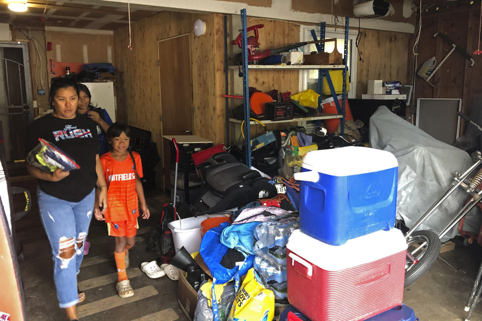 Nicole Gallano and two of her children exit their garage in Waianae, Hawaii, on Feb. 26, 2023. Hawaii's housing shortage has set off a population decline and grown so acute it has sparked widespread concern many of Hawaii's children won't be able to afford living in their homeland as adults. (AP Photo/Audrey McAvoy)