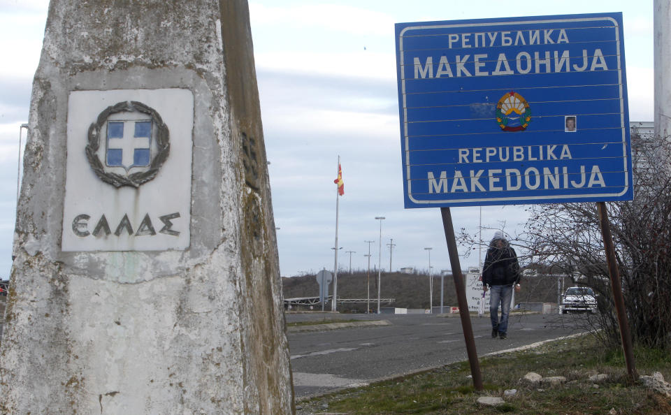 A man walks next to a road sign reading "Republic of Macedonia" and a Greek border stone at Bogorodica border crossing, on Macedonia's southern border with Greece, Tuesday, Feb. 12, 2019. Macedonian authorities began Monday removing official signs from government buildings to prepare for the country's new name: North Macedonia. (AP Photo/Boris Grdanoski)