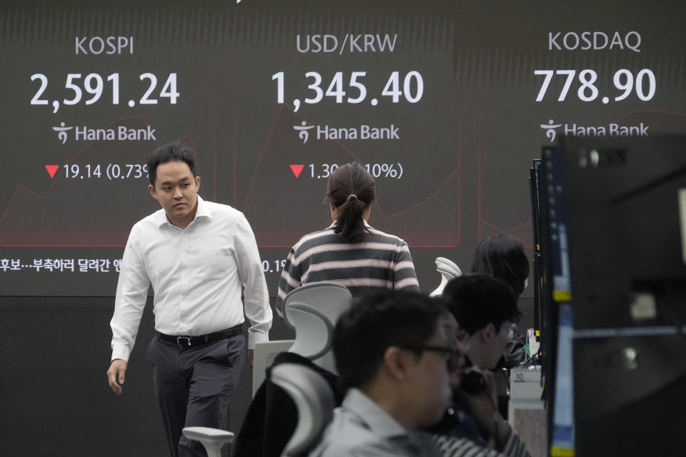 Currency traders pass by a screen showing the Korea Composite Stock Price Index (KOSPI), center left, and the foreign exchange rate between U.S. dollar and South Korean won, center, at the foreign exchange dealing room of the KEB Hana Bank headquarters in Seoul, South Korea, Tuesday, Oct. 8, 2024. (AP Photo/Ahn Young-joon)