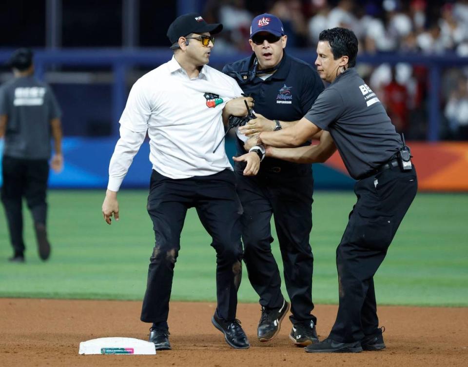 Cuban activist Antonio Fernandez is stopped at second base by stadium security after rushing the field during the game between the United States and Cuba at the World Baseball Classic semifinal at loanDepot Park in Miami, Fla. on Sunday, March 19, 2023.