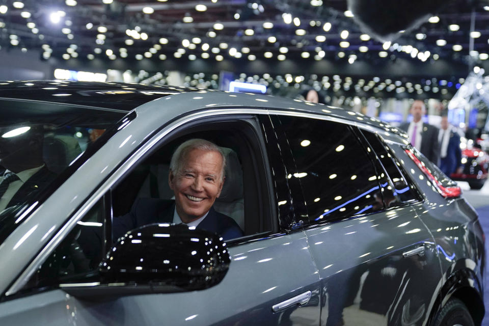 FILE - President Joe Biden drives a Cadillac Lyriq through the showroom during a tour at the Detroit Auto Show, Sept. 14, 2022, in Detroit. The Biden administration is awarding nearly $2 billion in grants to help restart or expand electric vehicle manufacturing and assembly sites in eight states, including the presidential battlegrounds of Michigan, Pennsylvania and Georgia. Grants totaling $1.7 billion will be issued by the Energy Department to create or retain thousands of union jobs and support auto-based communities that have long driven the U.S. economy, the White House said Thursday, July 11, 2024. (AP Photo/Evan Vucci, File)