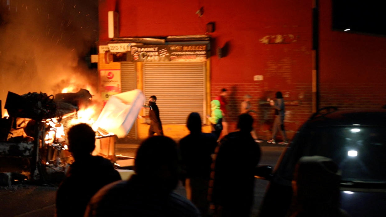 A man throws an item onto a fire during unrest in Harehills, Leeds, Britain, July 18, 2024 in this still image obtained from social media video.  ?@robin_singh? via Instagram/via REUTERS  THIS IMAGE HAS BEEN SUPPLIED BY A THIRD PARTY. MANDATORY CREDIT.