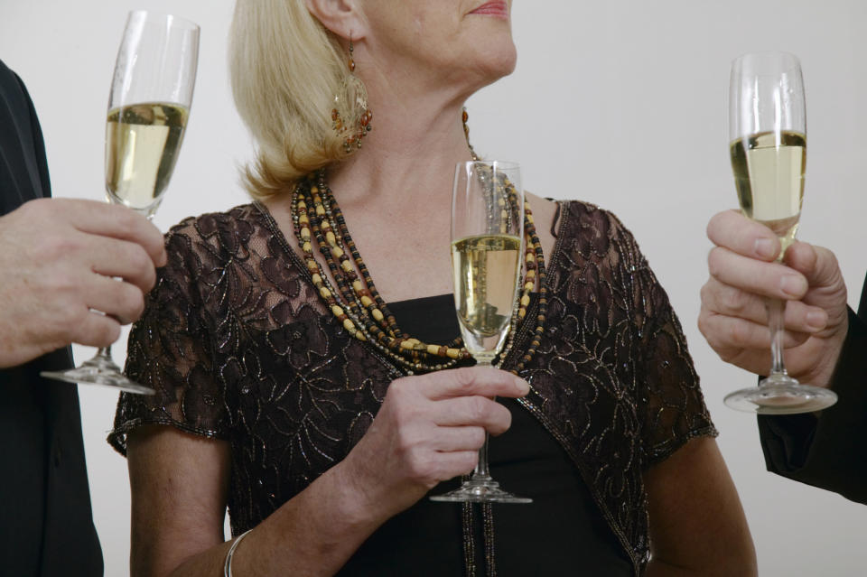 Woman standing between two men, all of them holding glasses of champagne