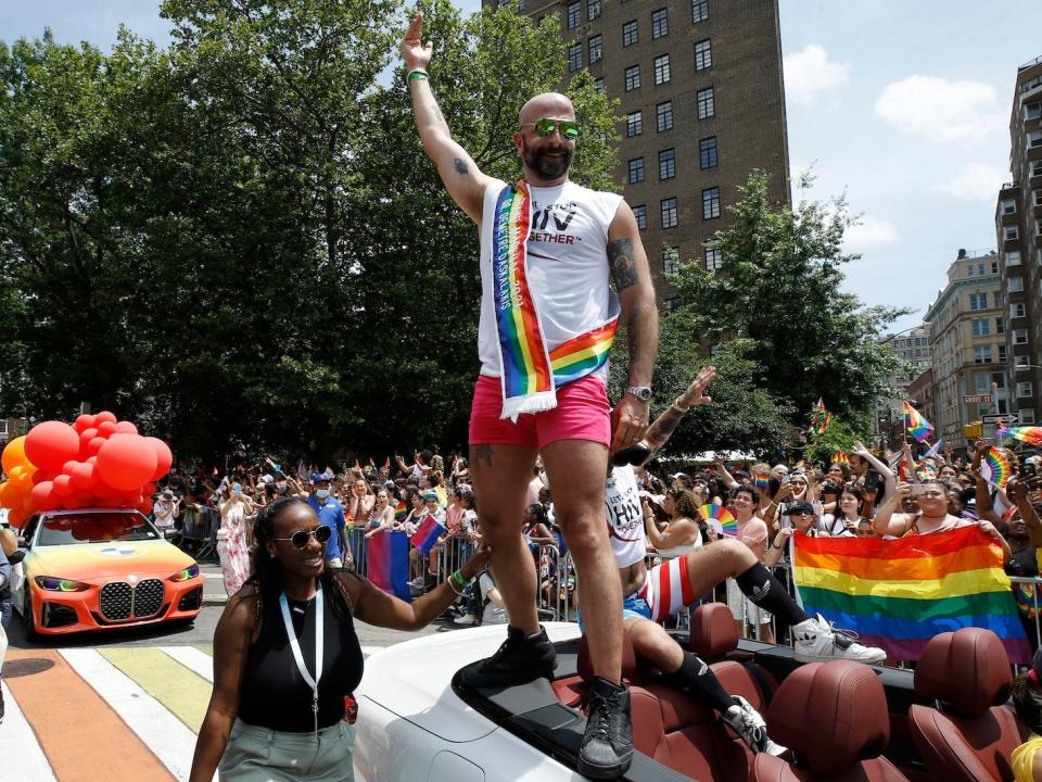 dr demetre in the 2021 pride parade, standing on a car and waving