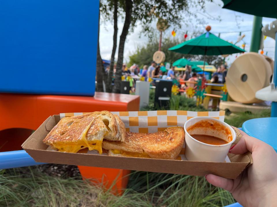 hand holding kids' grilled cheese and tomato soup meal from woody's lunchbox in hollywood studios