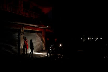 People use the light of a motorcycle to illuminate them as they talk on the street during a blackout in Caracas