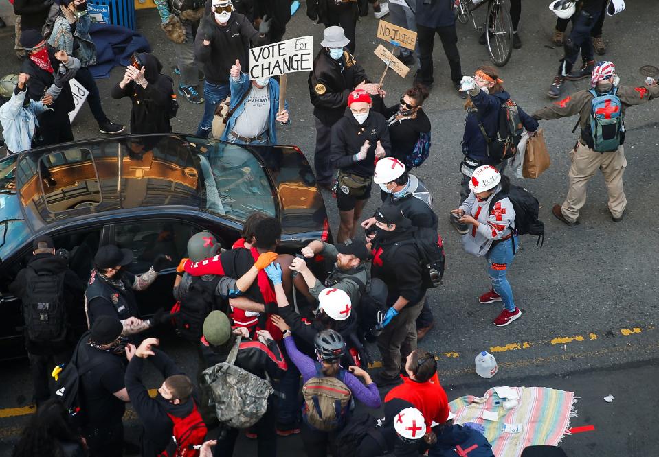 Photojournalist Alex Garland helps apply a tourniquet to the arm of a gunshot victim after a man drove into a Seattle protest crowd.