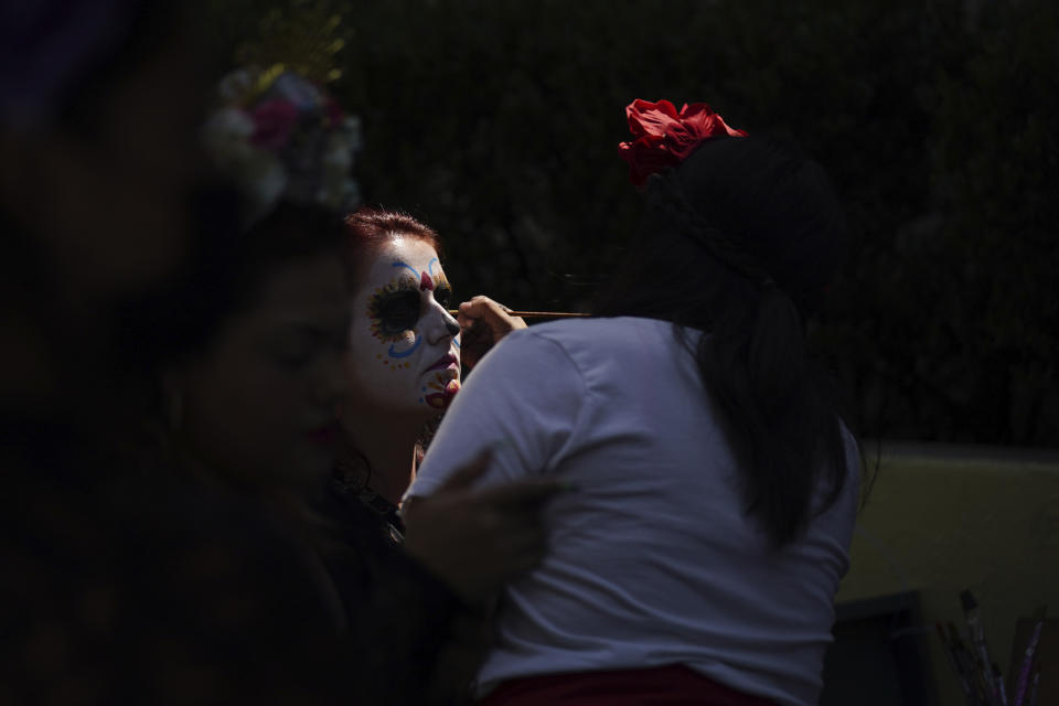 A woman has her face painted as a "Catrina" during Day of the Dead festivities in Mexico City, Sunday, Oct. 31, 2021. Altars and artwork from around the country were on display in a parade, as Mexicans honor the Day of the Dead. (AP Photo/Fernando Llano)