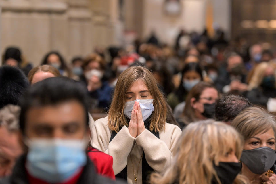 A woman wearing a mask prays at Midnight Mass on Christmas Eve in New York. Source: Getty