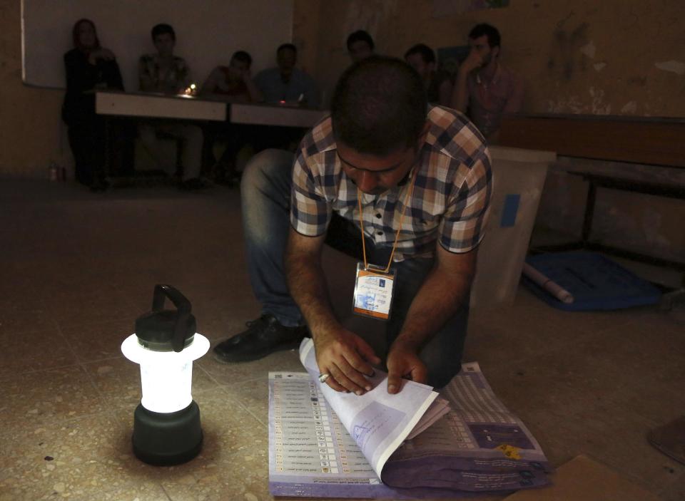An electoral worker counts ballots under lamplight, due to a power cut, as polls close at a polling center in Baghdad, Iraq, Wednesday, April 30, 2014. Iraqis braved the threat of bombs and other violence to vote Wednesday in parliamentary elections amid a massive security operation as the country slides deeper into sectarian strife. (AP Photo/Karim Kadim)
