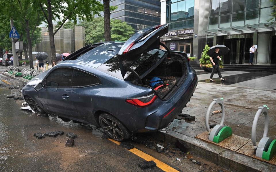 A car damaged by flood water is seen on the street after heavy rainfall at Gangnam district in Seoul - JUNG YEON-JE/AFP via Getty Images