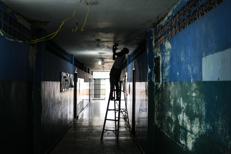 FILE - A worker fixes a water leak at a public school while students are out for summer vacation in Caracas, Venezuela, Wednesday, Aug. 10, 2022. A few days into their long break, teachers have been marching by the thousands around the country, threatening to strike when school resumes or possibly even to abandon their profession after the government paid them only a tiny fraction of their annual vacation bonus. (AP Photo/Matias Delacroix, File)