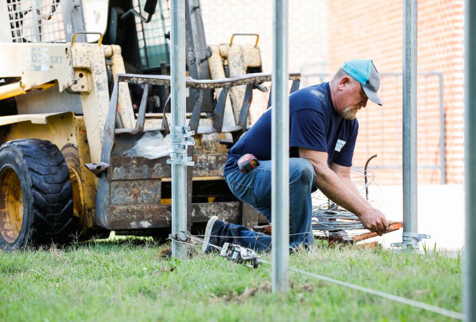 Anchor Fence installer Jason Overholser installs a fence in the playground area at Bissett Elementary School on Tuesday, Aug. 15, 2023 as part of security upgrades funded by the 2023 bond issue.