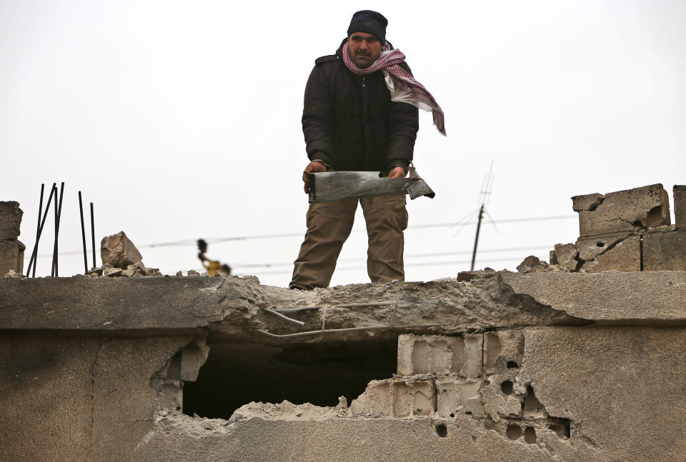 A Lebanese man holds a part of an exploded rocket that hit a house in the predominately Shiite town of Labweh, near the border with Syria, northeast Lebanon, Monday March 17, 2014. Several rockets struck Labweh not far from the predominantly Sunni town of Arsal, causing damage to a house but no casualties. Residents in Labweh said the rockets were fired from Arsal raising tension between the two towns. Angry residents in Labweh closed the main road leading to Arsal with sand barriers preventing people from entering or leaving as about 20 armed Hezbollah manned the roadblocks. (AP Photo/Hussein Malla)