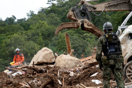 Rescue workers and Japan Self-Defense Force soldiers search for missing people at a landslide site caused by a heavy rain in Kumano Town, Hiroshima Prefecture, western Japan, July 11, 2018. REUTERS/Issei Kato