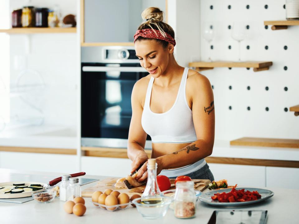 Woman in gym clothing preparing food in a kitchen.