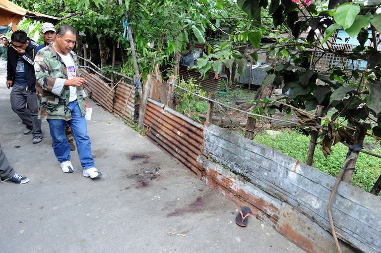 Police investigators inspect the scene of shooting in Kawit, south of Manila, on January 4, 2013. The gunman, armed with a semi-automatic pistol, killed seven people and wounded 11 others as he rampaged through a slum on the outskirts of the Philippine capital