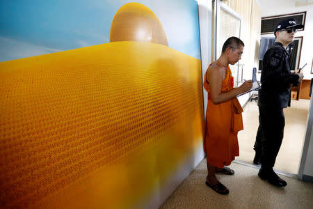 A Department of Special Investigation (DSI) officer stands next to a Buddhist monk from the Wat Phra Dhammakaya temple during an inspection of the temple, in Pathum Thani province, Thailand March 10, 2017. REUTERS/Chaiwat Subprasom