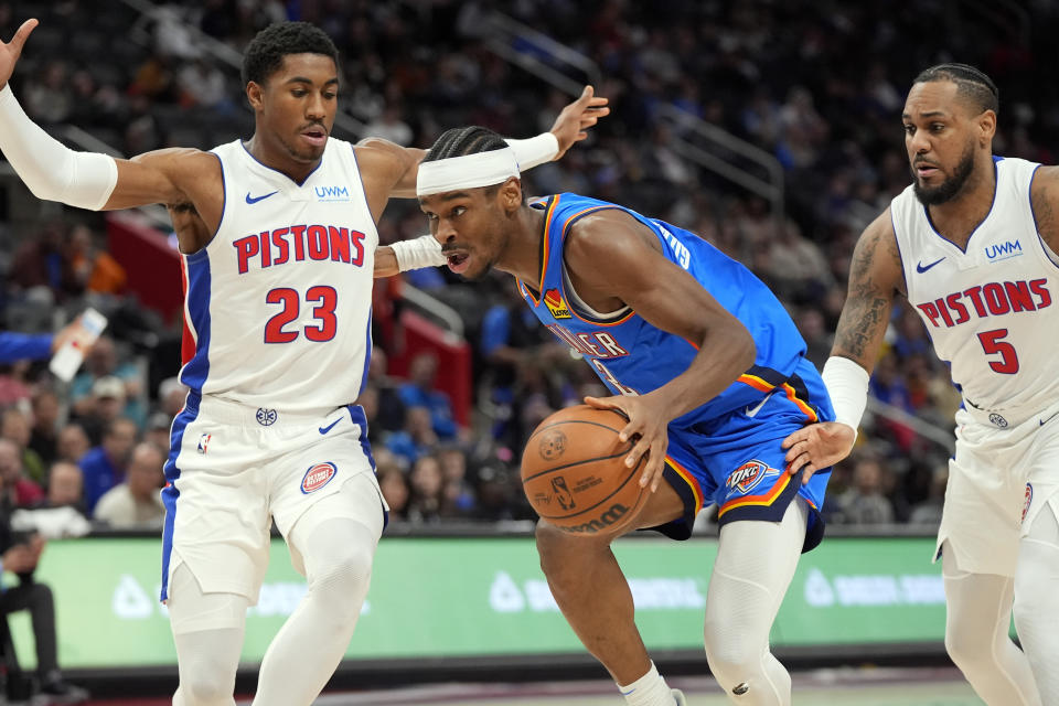 Oklahoma City Thunder guard Shai Gilgeous-Alexander (2) drives through Detroit Pistons guard Jaden Ivey (23) and guard Monte Morris (5) during the second half of an NBA basketball game, Sunday, Jan. 28, 2024, in Detroit. (AP Photo/Carlos Osorio)