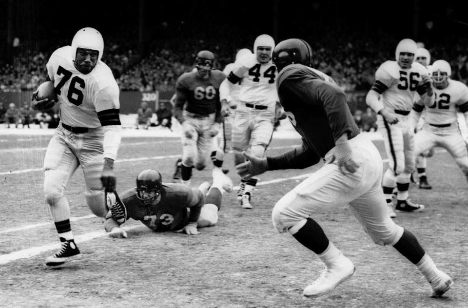 Cleveland Browns fullback Marion Motley (76) gains a yard before being pulled down by New York Giants' Jim Duncan, right, in 1950.