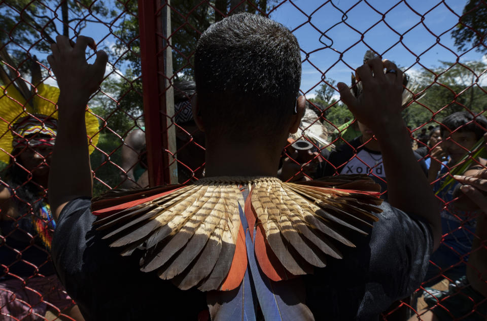 Guarani Mbya protesters stand on both sides of a fence at the permitter of a development project for apartment buildings by real estate company Tenda, which is next to their community's land in Sao Paulo, Brazil, Thursday, Jan. 30, 2020. The tension between a builder with projects in nine Brazilian states and a 40-family indigenous community is a microcosm of what’s playing out elsewhere in the country. (AP Photo/Andre Penner)