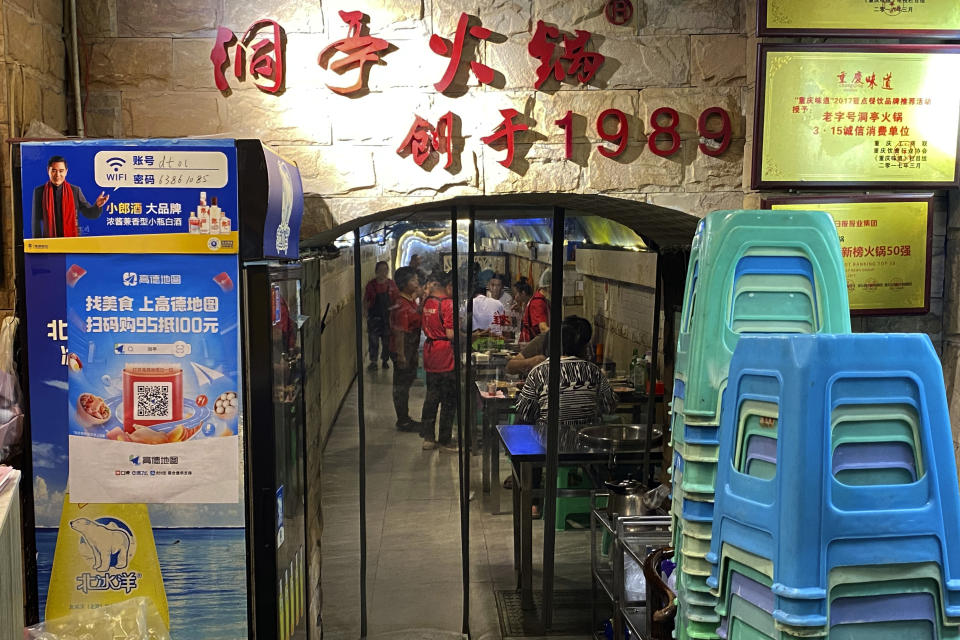 Customers eat hotpot in a hotpot restaurant located in a converted WWII-era air raid shelter in southwestern China's Chongqing Municipality, Saturday, Aug. 20, 2022. The city of Chongqing, dubbed one of China's four "furnace" cities, is known for both soaring temperatures and spicy cuisine - notably its hotpot, a peppery bubbling tabletop broth into which diners dunk bite-size pieces of food to cook and eat. (AP Photo/Mark Schiefelbein)