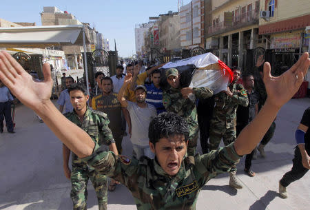 Mourners carry the coffin of Salah al-Wa'ili, a fighter from the Iraqi Shi'ite group Asa'ib Ahl al-Haq, during his funeral in Najaf July 12, 2014. REUTERS/Alaa Al-Marjani