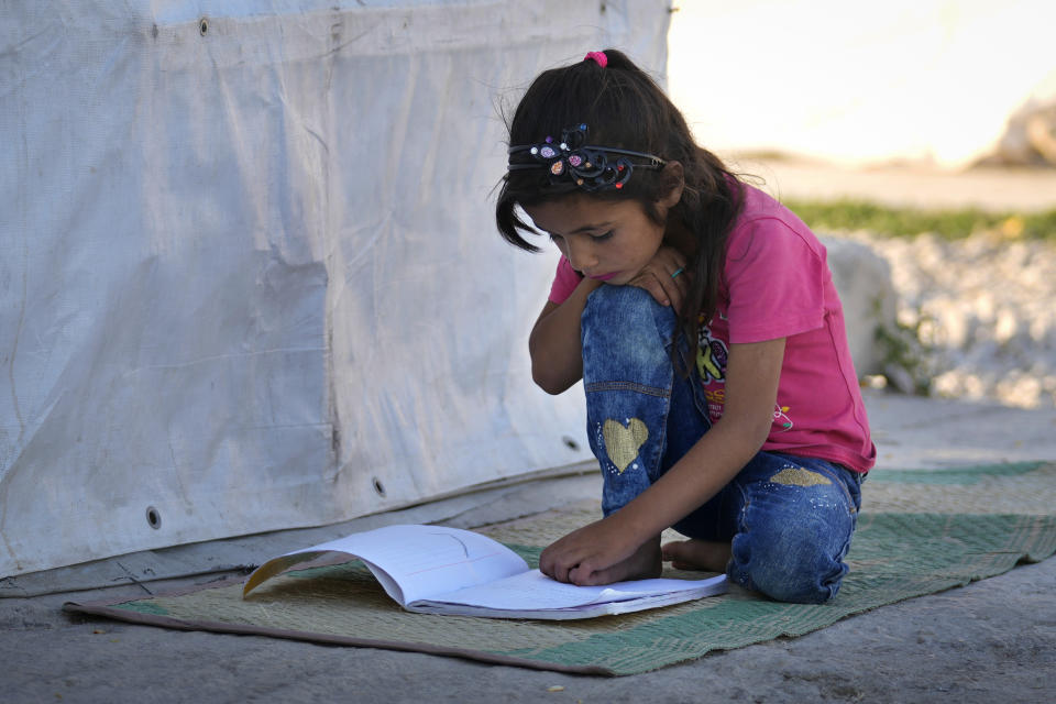 A Syrian child studies outside her family's tent at a refugee camp in the town of Bar Elias, in the Bekaa Valley, Lebanon, July 7, 2022. The Lebanese government’s plan to start deporting Syrian refugees has sent waves of fear through vulnerable refugee communities already struggling to survive in their host country. Many refugees say being forced to return to the war shattered country would be a death sentence. (AP Photo/Bilal Hussein)
