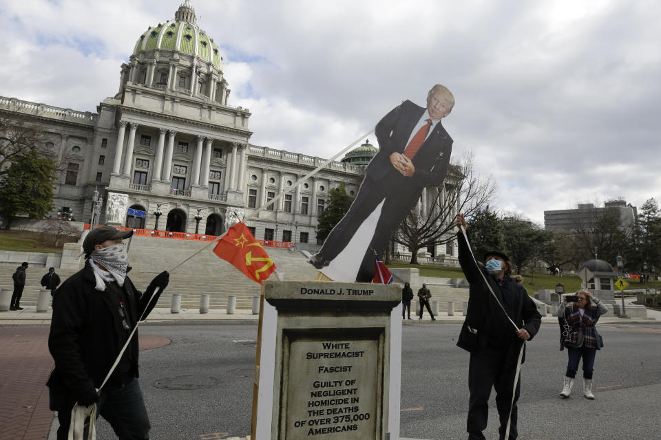 El activista político Gene Stilp (derecha) tira de una correa atada a una fotografía de contorno recortado del presidente Donald Trump durante una manifestación frente al Capitolio estatal de Pensilvania, el domingo 17 de enero de 2021, en Harrisburg, Pensilvania (AP Foto/Jacqueline Larma)