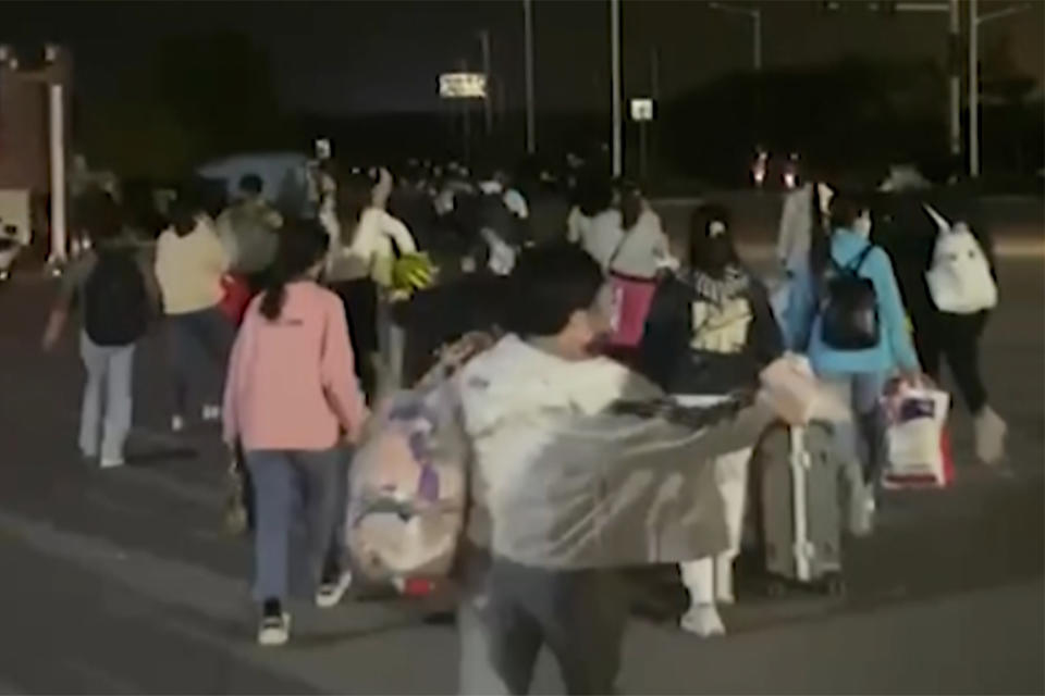 In this photo taken from video footage and released by Hangpai Xingyang, people with suitcases and bags are seen leaving from a Foxconn compound in Zhengzhou in central China's Henan Province on Saturday, Oct. 29, 2022. Workers in a Foxconn facility in the central Chinese city of Zhengzhou appear to have left the facility to avoid COVID-19 curbs, with many traveling by foot days after an unknown number of factory workers were quarantined in the facility following a virus outbreak. (Hangpai Xingyang via AP)